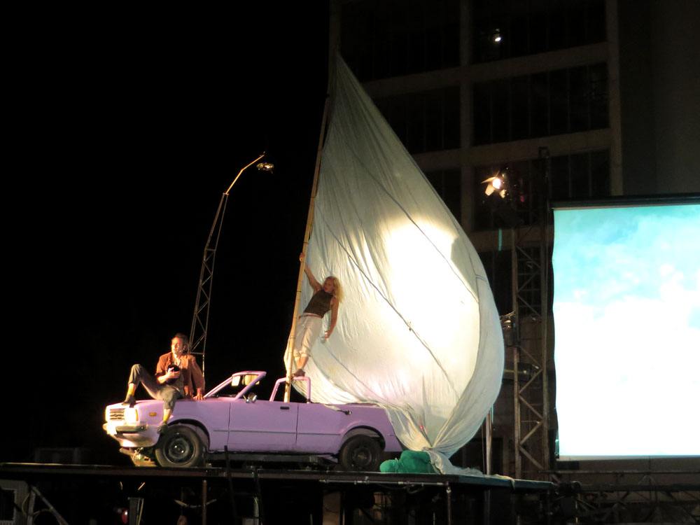Alter Ford Mustang mit großem weißen Segel auf der Bühne mit zwei Schauspieler/innen